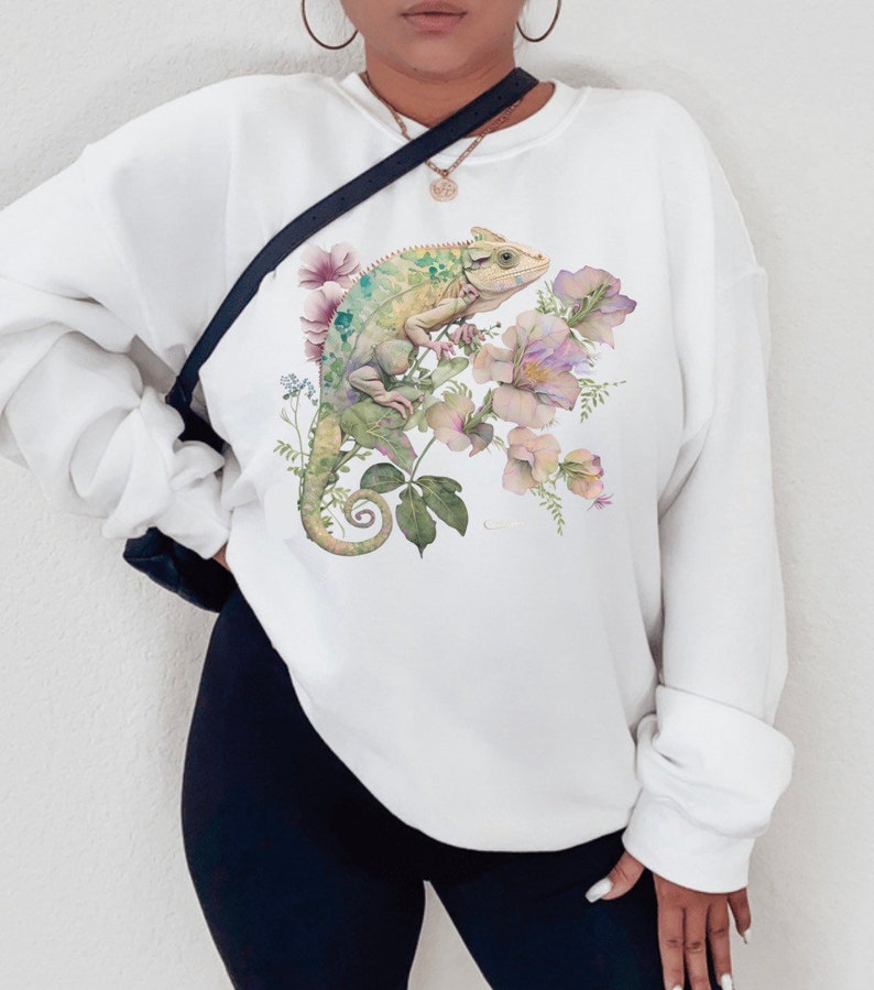 May include: White sweatshirt with a green chameleon and pink flowers printed on the front.