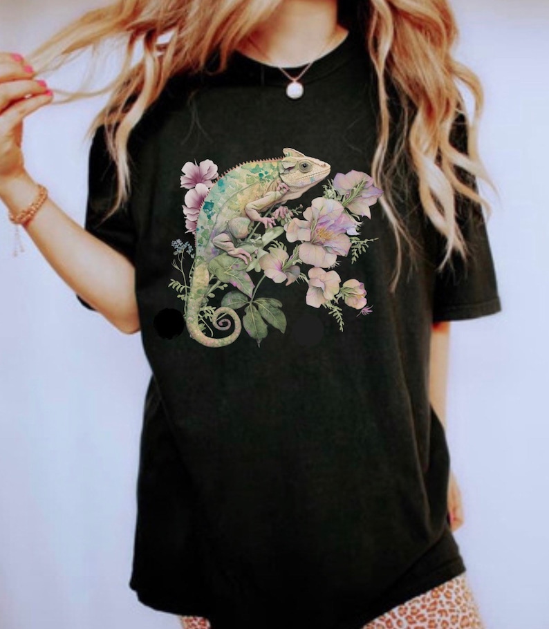 May include: Black t-shirt featuring a green chameleon and pink flowers printed on the front.