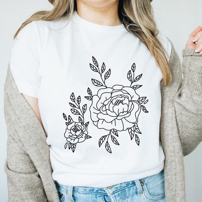 K&ouml;nnte beinhalten: Ein wei&szlig;es T-Shirt mit einer schwarzen Linienzeichnung von zwei Blumen und Bl&auml;ttern.