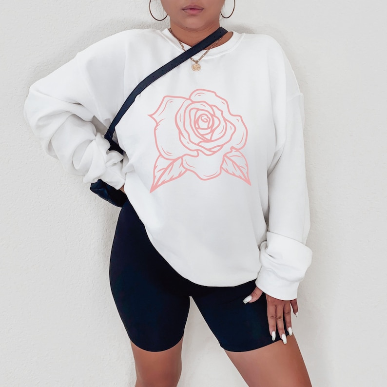 May include: White sweatshirt with a pink outline of a rose on the front.