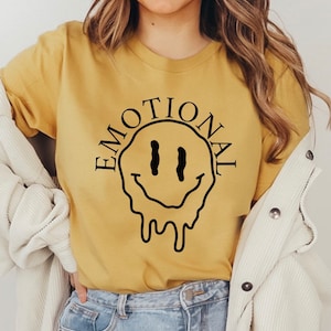 May include: A yellow t-shirt with a black dripping smiley face and the word "EMOTIONAL" around it.