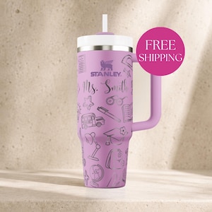 May include: A light purple Stanley tumbler with a white lid and straw, featuring a handle and a repeating pattern of school-themed line art including a bus, globe, books, and the text Ms. Smith printed in a cursive script on the front surface.