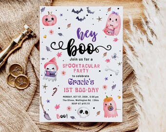 Op de afbeelding: Een Halloween-uitnodiging met de tekst "hey boo" en "Join us for a Spooktacular Party to celebrate Gracie's 1st Boo-Day". De uitnodiging bevat illustraties van geesten, pompoenen, vleermuizen en sterren.