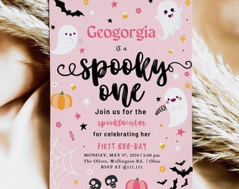May include: A pink rectangular invitation card featuring white ghosts, black bats, orange pumpkins, and skulls. The text reads: Geogorgia is a spooky one, Join us for the spooktacular for celebrating her FIRST BOO-DAY, MONDAY, MAY 07, 2024, 5:00 pm, The Olives, Wellington Rd., Ohio, RSVP AT @111.111.