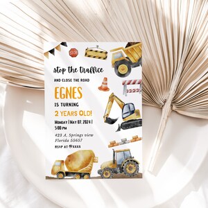 Puede incluir: Invitación de cumpleaños con temática de construcción, con ilustraciones de vehículos de construcción, como un camión volquete y una hormigonera. El texto dice "stop the traffice" y anuncia la fiesta de cumpleaños de un niño de 2 años.