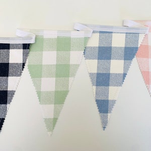 May include: A set of four fabric pennant flags with a gingham pattern. The flags are black and white, green and white, blue and white, and pink and white.