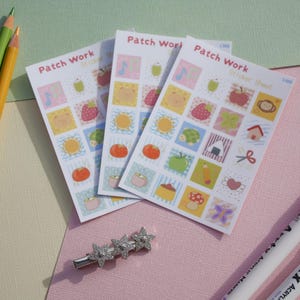 May include: Three rectangular sticker sheets labelled Patch Work Sticker Sheet, each featuring a grid of small colourful illustrations including fruits, animals, and objects. A silver star-shaped hair clip is positioned below the sticker sheets.