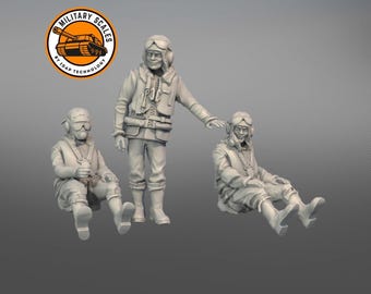 May include: Three unpainted plastic figurines of World War II pilots wearing flight suits and helmets. The figures are posed in different positions, one standing and two sitting.