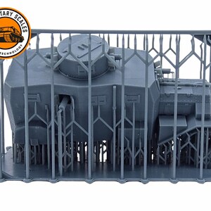 May include: A gray 3D printed model of a tank, enclosed in a cage-like structure. The tank has a large turret and a detailed design. The model is printed by "Military Scales by 3D-AP Technology".