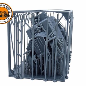 May include: A gray 3D printed model of a tank inside a gray 3D printed cage. The cage is made of a series of vertical and horizontal bars. The tank is partially visible through the bars. The image is labeled "Military Scales by 3D-RAP Technology".
