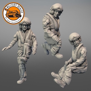 Op de afbeelding: Drie grijze plastic figuren van militair personeel met helmen en vluchtpakken. De figuren zijn in verschillende actiehoudingsposes geposeerd.