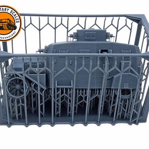 May include: A gray 3D printed model of a tank inside a gray plastic crate. The crate has a lattice design and the tank is partially visible. The tank is a military vehicle with wheels and a turret. The image is labeled "Military Scales by 3Drap Technology".