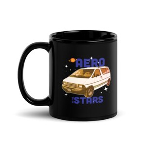 May include: Black ceramic coffee mug featuring a white Ford Aerostar van graphic. The van is surrounded by stars and the text "Aero in the Stars" is printed below the van.