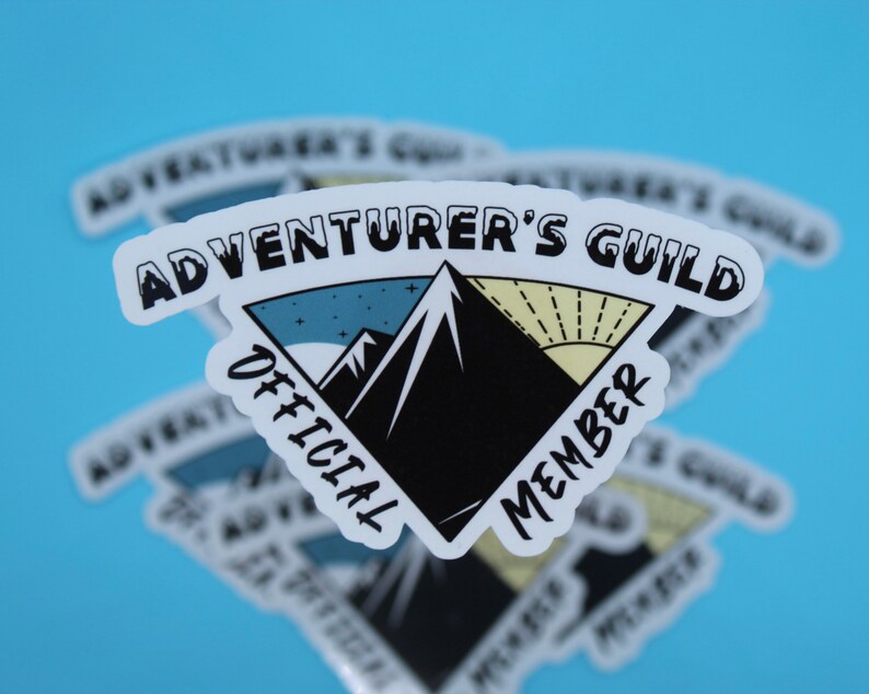 May include: White sticker with a black mountain range and a yellow sun. The text "Adventurer's Guild" is at the top of the sticker, and "Official Member" is on the sides of the sticker.