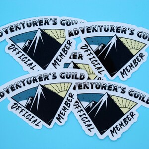 May include: Five white stickers with a black mountain range design and the text "Adventurer's Guild" in a curved white banner. The text "Official Member" is also on each sticker in a curved white banner.