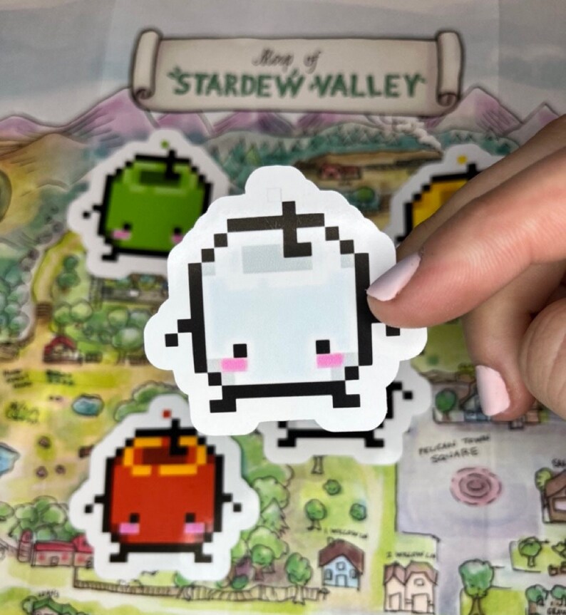 May include: A selection of pixelated Stardew Valley stickers. The stickers depict a white ghost-like character with pink cheeks, a green apple, and a red apple. The background is a map of Stardew Valley, with the title at the top.