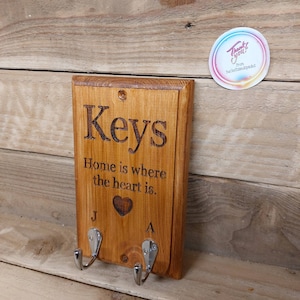 May include: Wooden key holder with two hooks. The sign reads "Keys" and "Home is where the heart is." with a small heart symbol.