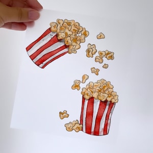 Op de afbeelding: Twee rood-wit gestreepte popcorncontainers met popcorn dat uit de bovenkant stroomt. De popcorn is getekend als kleine, glimlachende gezichten.