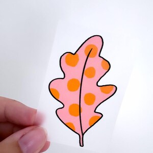 May include: A pink leaf with orange polka dots. The leaf is outlined in black.