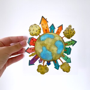 May include: A watercolour painting of a blue globe surrounded by colourful houses, trees, and arrows. The houses are all different colours and have windows and doors. The trees are green and have brown trunks. The arrows are pointing in different directions.