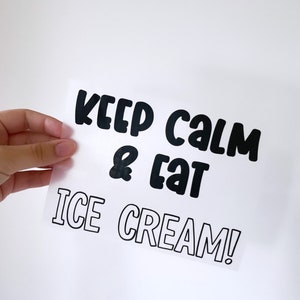 Könnte beinhalten: Ein weißes Blatt Papier mit schwarzem Text, der "Keep Calm & Eat Ice Cream!" lautet. Der Text ist in einer fetten, verspielten Schriftart.