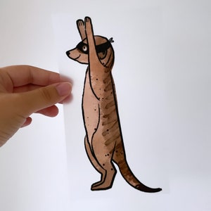 Op de afbeelding: Een bruine en zwarte meerkat met een zwart oogmasker, met zijn armen in de lucht.