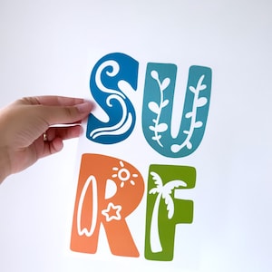 Può includere: Un adesivo da parete colorato con la parola "SURF" in lettere stilizzate. Ogni lettera presenta un design diverso, tra cui un'onda, una palma e una tavola da surf.
