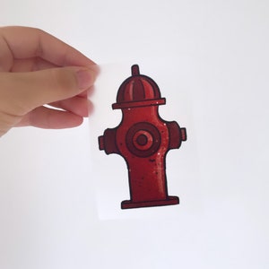 May include: A red fire hydrant sticker with a black outline and a white circle in the centre. The sticker is on a clear background.