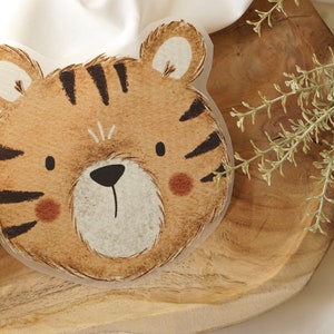 Può includere: Un'illustrazione di un muso di tigre, con pelliccia marrone e strisce nere, un naso nero e guance marroni. Lo sfondo è bianco.