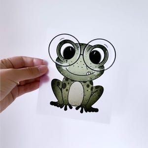 Könnte beinhalten: Ein Comic-Frosch mit großen, runden Brillen und einem grün-braun gefleckten Körper.