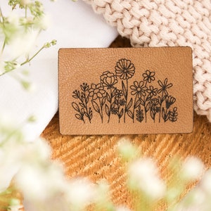 Peut inclure: Un patch en cuir marron avec un motif floral noir. Le motif présente une variété de fleurs et de feuilles.