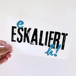 May include: A white card with the text "eSKALIERt" in black and "ha!" in blue.