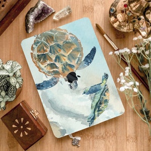 May include: A watercolor painting of two sea turtles swimming in the ocean. The larger turtle is brown and green with a blue shell. The smaller turtle is green and blue with a yellow shell. The background is a light blue watercolor wash.