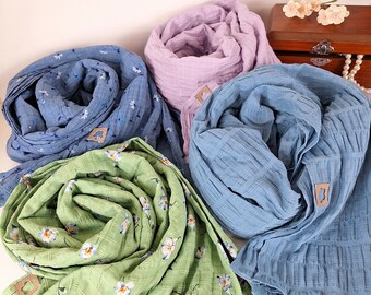 Puede incluir: Cuatro bufandas de tela en diferentes colores y patrones. Las bufandas están dobladas y dispuestas sobre una superficie blanca. Las bufandas están hechas de una tela suave y ligera y presentan un estampado floral.
