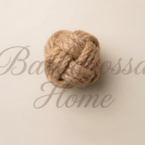 K&ouml;nnte beinhalten: Ein dekorativer Seilknoten in nat&uuml;rlicher Beige-Farbe. Der Knoten befindet sich mittig auf einem hellbeigen Hintergrund mit dem Text "Barossa Home" in Schreibschrift.