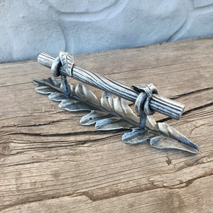 以下が含まれることがあります： 葉のデザインとねじれた枝のようなハンドルが付いた銀色の金属製のドアハンドルです。