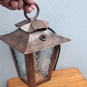 Vintage smeedijzeren buitenlantaarn met patina en getextureerd glas