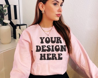 May include: A pink sweatshirt with the text "YOUR DESIGN HERE" in black.
