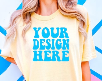 Könnte beinhalten: Ein hellgelbes T-Shirt mit einem blauen Retro-Schriftzug, der "YOUR DESIGN HERE" lautet.