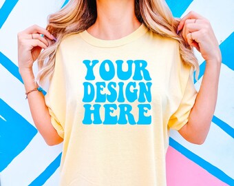 Könnte beinhalten: Ein hellgelbes T-Shirt mit einem blauen Retro-Schriftzug, der "YOUR DESIGN HERE" lautet.