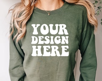 Op de afbeelding: Een groen sweatshirt met lange mouwen met de tekst "YOUR DESIGN HERE" in wit.