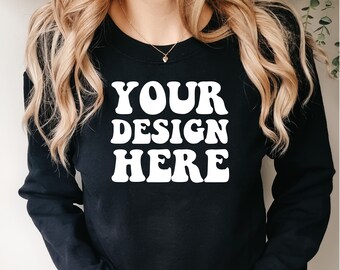 Puede incluir: Una sudadera negra con el texto "YOUR DESIGN HERE" en letras blancas. La sudadera la lleva puesta una persona con el pelo largo y rubio.
