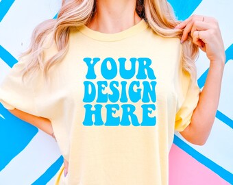 Könnte beinhalten: Ein hellgelbes T-Shirt mit einem blauen Retro-Schriftzug, der "YOUR DESIGN HERE" lautet.