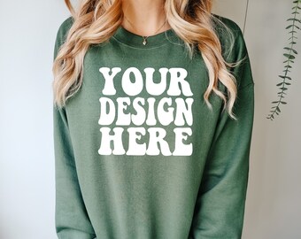 Op de afbeelding: Een groen sweatshirt met de tekst "YOUR DESIGN HERE" in witte retro-lettering.
