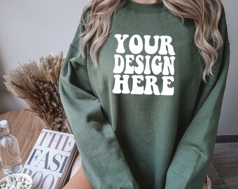 Op de afbeelding: Een groen sweatshirt met de tekst "YOUR DESIGN HERE" in witte retro-letters.