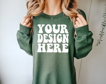 May include: A green sweatshirt with the text "YOUR DESIGN HERE" in white retro-style lettering.