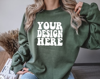 May include: A green sweatshirt with the text "YOUR DESIGN HERE" in white letters. The sweatshirt has long sleeves and a crew neck.