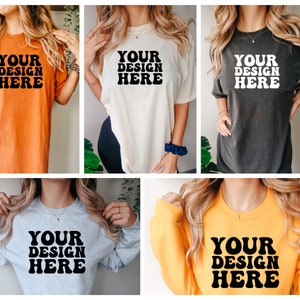May include: Five different t-shirts and sweatshirts with the text "YOUR DESIGN HERE" in a retro font. The shirts are in various colors, including orange, white, gray, black, and yellow.