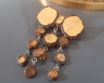 May include: Gold and brown dangle earrings with a circular design. The earrings are made of wood and metal.