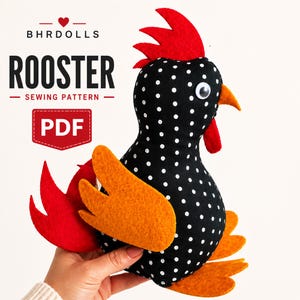 May include: A black fabric rooster with white polka dots, featuring a red felt comb and tail, orange felt wings and feet, and a googly eye. Text on the image reads BHRDOLLS ROOSTER SEWING PATTERN PDF. The rooster has a yellow beak and red wattle.
